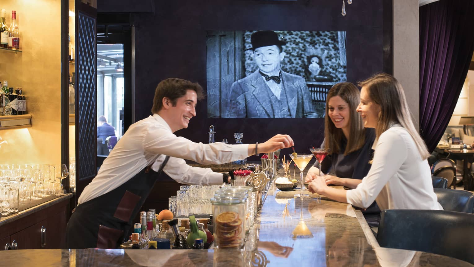 Bar and lounge at luxury hotel with two women drinking and a bartender serving cocktails